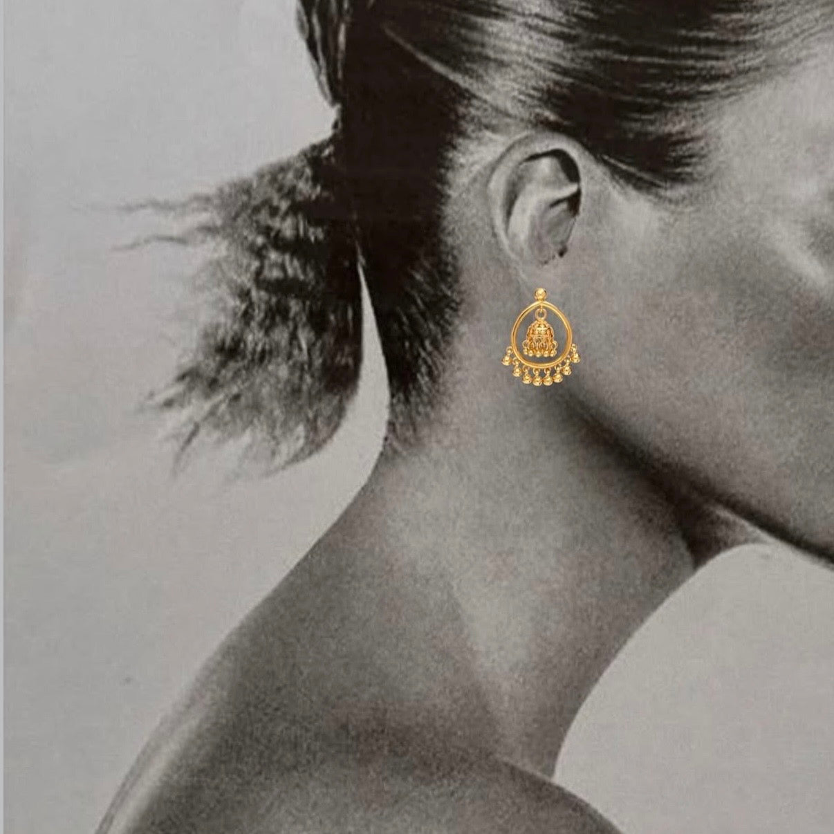Gold earring worn by a person with a neutral background