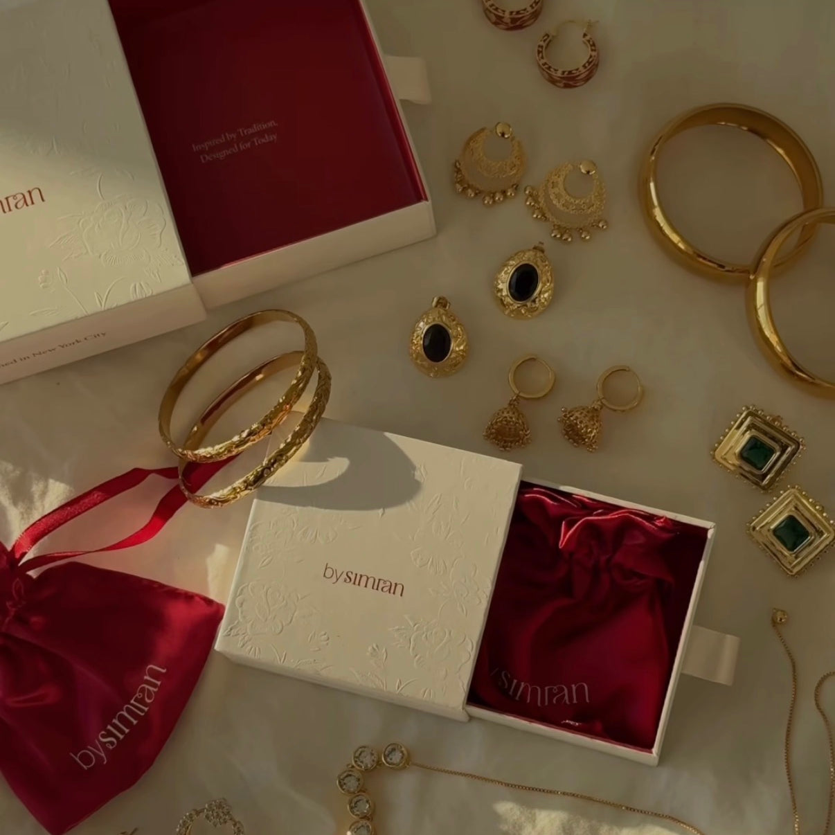 Gold jewelry set including earrings and bracelets on a white surface with a branded box.