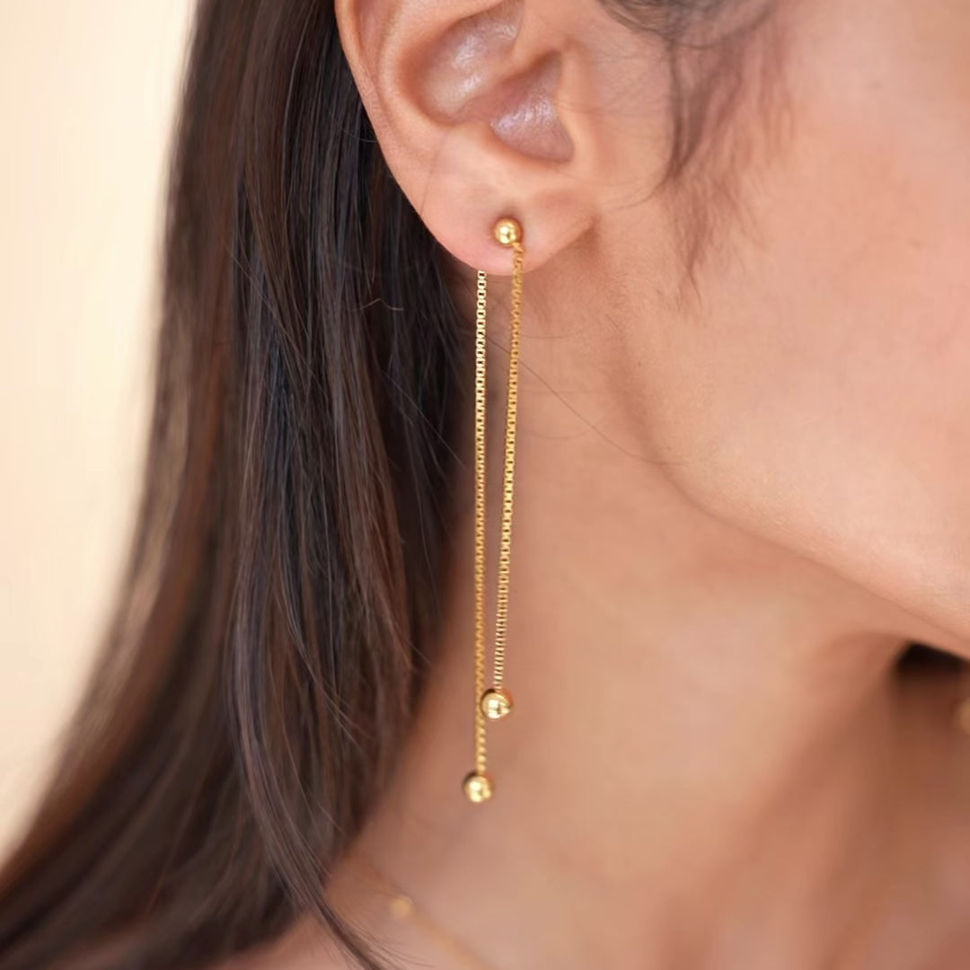 video of gold chain ball earrings, model is moving her head to show the earring 