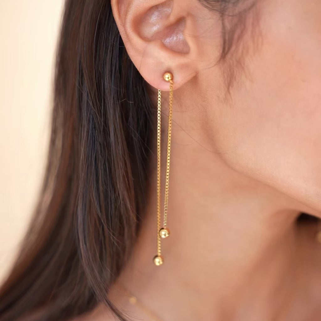 video of gold chain ball earrings, model is moving her head to show the earring 